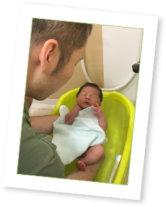 お父さんが赤ちゃんをお風呂に入れている写真 株式会社nft